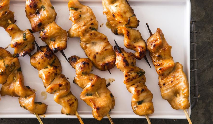 This undated photo provided by America's Test Kitchen in July 2018 shows chicken satay with spicy peanut dipping sauce in Brookline, Mass. This recipe appears in the cookbook “All Time Best Appetizers.” (Joe Keller/America's Test Kitchen via AP)