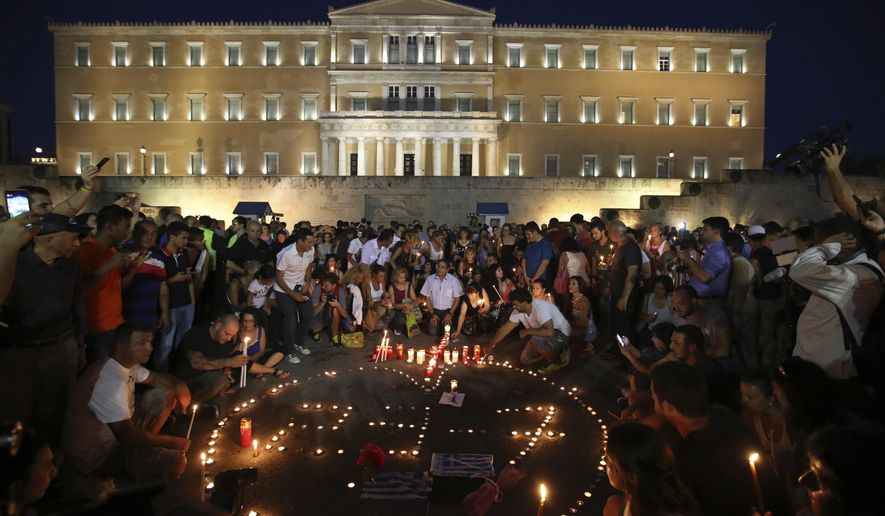 People gather outside the Greek Parliament in Athens, Monday, July 30, 2018 in memory of victims of a deadly wildfire a week ago. The date of July 23 is marked with candles. More than 90 people died in the fire that gutted resorts east of Athens, the deadliest Greek fire in recent history. (AP Photo/Thanassis Stavrakis)