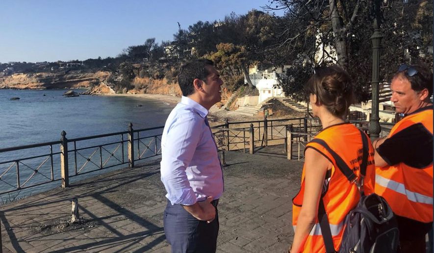 Greece's Prime Minister Alexis Tsipras visits the burnt area of Mati, east of Athens, Monday, July 30, 2018. Fire officials in Greece raised the death toll from a wildfire that raged through the Mati coastal area east of Athens to 91 and reported that 25 people were still missing Sunday. (Greek Prime Minister's Office via AP)