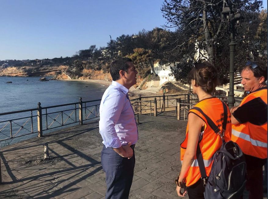 Greece's Prime Minister Alexis Tsipras visits the burnt area of Mati, east of Athens, Monday, July 30, 2018. Fire officials in Greece raised the death toll from a wildfire that raged through the Mati coastal area east of Athens to 91 and reported that 25 people were still missing Sunday. (Greek Prime Minister's Office via AP)
