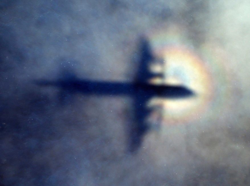 FILE - In this March 31, 2014 file photo, the shadow of a Royal New Zealand Air Force P3 Orion is seen on low level cloud while the aircraft searches for missing Malaysia Airlines Flight MH370 in the southern Indian Ocean, near the coast of Western Australia. An independent investigation report released Monday, July 30, 2018, more than four years after Malaysia Airlines Flight 370 disappeared highlighted shortcomings in the government response that exacerbated the mystery.(AP Photo/Rob Griffith, File)