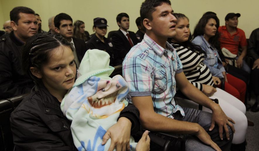 FILE - In this June 3, 2013 file photo, Dolores Lopez, holding her baby Jorge, left, Luis Olmedo, second from left, and Raquel Villalba third from left, attend their court hearing in the "Curuguaty" case, in Asuncion, Paraguay. On June 15, 2012, 11 landless farmers and six police officers were killed in a shooting during a violent eviction of farmers by police from the Marina Cue lands near Curuguaty. The country's Supreme Court on Friday, July 27, 2018 acquitted the group of small farmers who had been convicted for the assassination of the six police officers, citing not enough evidence. (AP Photo/Jorge Saenz, File)