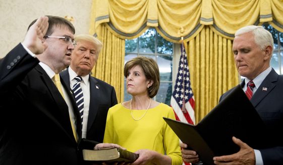 President Donald Trump, second from left, watches as Vice President Mike Pence, right, swears in Robert Wilkie, left, as secretary of the Department of Veterans Affairs during a ceremony in the Oval Office of the White House, Monday, July 30, 2018, in Washington. Also pictured is Wilkie&#39;s wife Julia, center. (AP Photo/Andrew Harnik) ** FILE **
