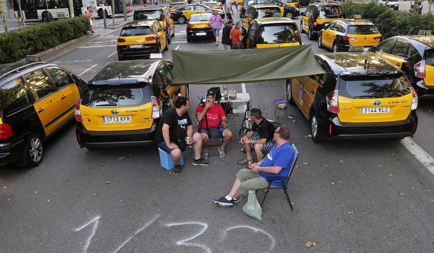 Taxi drivers block the Gran Via avenue in Barcelona, Spain, Monday, July 30, 2018. Taxi drivers in Barcelona are blocking traffic on a major thoroughfare as part of an indefinite strike to protest the use of ride-hailing apps like Uber and Cabify. (AP Photo/Manu Fernandez)