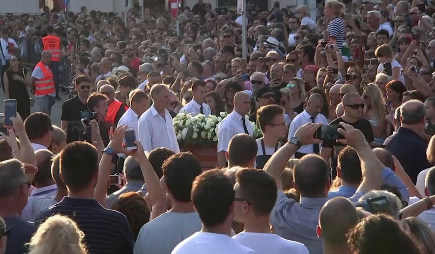 In this image taken from video, people gather as the coffin carrying Oliver Dragojevic is taken through Split, Tuesday July 31, 3018. Tens of thousands of people bid an emotional farewell on Tuesday to Oliver Dragojevic, commemorating one of the most popular pop singers in the former Yugoslavia who was adored for his songs celebrating love and the Adriatic Sea. (AP Photo)