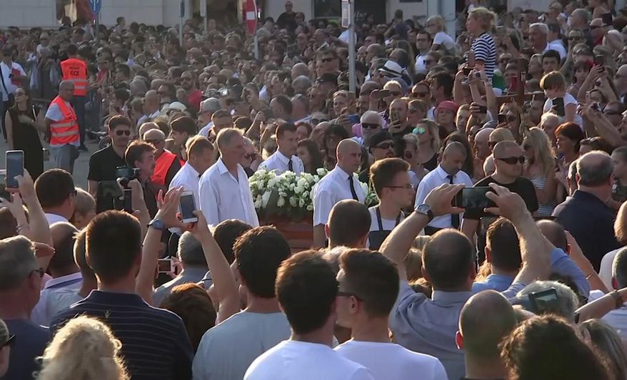 In this image taken from video, people gather as the coffin carrying Oliver Dragojevic is taken through Split, Tuesday July 31, 3018. Tens of thousands of people bid an emotional farewell on Tuesday to Oliver Dragojevic, commemorating one of the most popular pop singers in the former Yugoslavia who was adored for his songs celebrating love and the Adriatic Sea. (AP Photo)