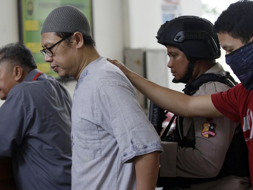 Indonesian militant Zainal Anshori who is also the leader of Jemaah Anshorut Daulah, a network of militants that supports the Islamic State group, is escorted by police officers upon arrival for a hearing at South Jakarta District Court in Jakarta, Indonesia Tuesday, July 31, 2018. The court on Tuesday outlawed the network of almost two dozen extremist groups following a series of deadly attacks over the past two years. (AP Photo/Tatan syuflana)