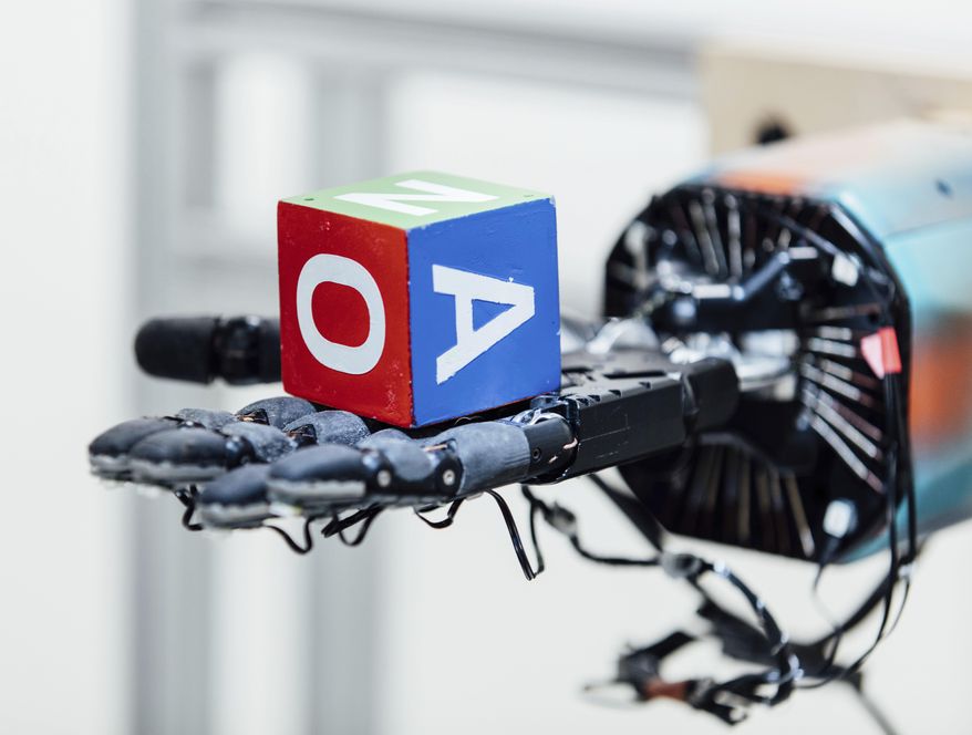 This undated photo provided by OpenAI shows a robotic hand holding a cube at the company's research lab in San Francisco. The hand, called Dactyl, has a single job, and that’s to rotate a cube until the letter facing up matches a random selection. (Eric Louis Haines/OpenAI via AP)