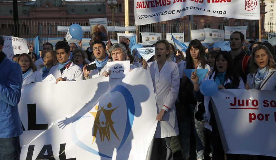 In this July 15, 2018 photo, medical doctors protest against efforts to legalize abortion, in front of Government House in Buenos Aires, Argentina. Hundreds of physicians have staged anti-abortion protests as an abortion rights bill moves toward a vote in the Senate. (AP Photo/Jorge Saenz)