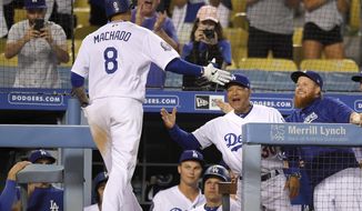 Los Angeles Dodgers&#39; Manny Machado, left, is congratulated by manager Dave Roberts, center, and Justin Turner after hitting a solo home run during the ninth inning of a baseball game against the Milwaukee Brewers, Monday, July 30, 2018, in Los Angeles. Milwaukee won 5-2. (AP Photo/Mark J. Terrill)