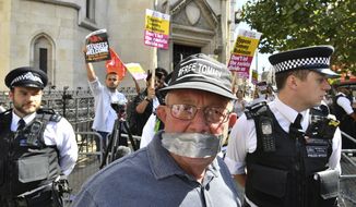 A supporter of Tommy Robinson in the foreground poses for a photo as Stand Up to Racism demonstrators protest outside the Royal Courts of Justice, in London, Wednesday, Aug. 1, 2018.  A British court has ordered prominent far-right activist Tommy Robinson to be released on bail while he appeals a finding of contempt of court. Robinson had been jailed for 13 months after live-streaming outside a criminal trial in violation of reporting restrictions. Court. (John Stillwell/PA via AP)