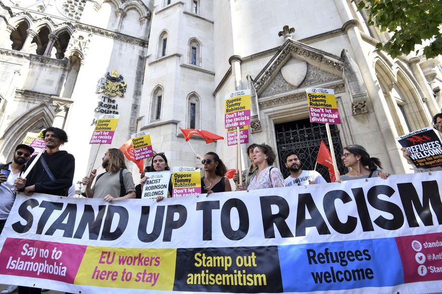 Demonstrators against far-right activist Tommy Robinson protest outside the Royal Courts of Justice, in London, Wednesday, Aug. 1, 2018.  A British court has ordered prominent far-right activist Tommy Robinson to be released on bail while he appeals a finding of contempt of court. Robinson had been jailed for 13 months after live-streaming outside a criminal trial in violation of reporting restrictions. Court. (John Stillwell/PA via AP)