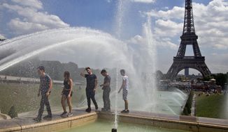 People cool off as they walk along the fountain of Warsaw near Eiffel Tower in Paris, France, Wednesday, Aug, 1, 2018. Temperatures in Paris are forecast to reach 3O degrees C (86 F) on Wednesday. (AP Photo/Michel Euler)