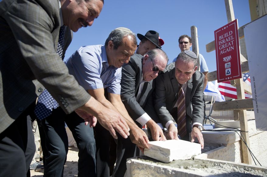 U.S. Governor Mike Huckabee, 2nd right, lays a brick at a new housing complex in the West Bank settlement of Efrat, Wednesday, Aug. 1, 2018. (AP Photo/Oded Balilty)
