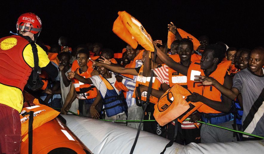 Migrants wait to be rescued off the coast of Libya in the early hours of Thursday night, Aug. 2, 2018, as rescuers throw life jackets at them and urge them to stay calm. Rescuers from the Spanish non -profit Open Arms saved 87 migrants off the coast of Libya in a dramatic nighttime operation. The group included eight minors. (AP Photo/Valerio Nicolosi)