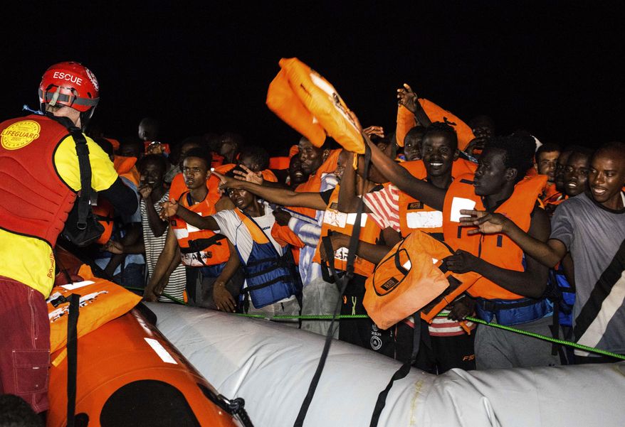 Migrants wait to be rescued off the coast of Libya in the early hours of Thursday night, Aug. 2, 2018, as rescuers throw life jackets at them and urge them to stay calm. Rescuers from the Spanish non -profit Open Arms saved 87 migrants off the coast of Libya in a dramatic nighttime operation. The group included eight minors. (AP Photo/Valerio Nicolosi)
