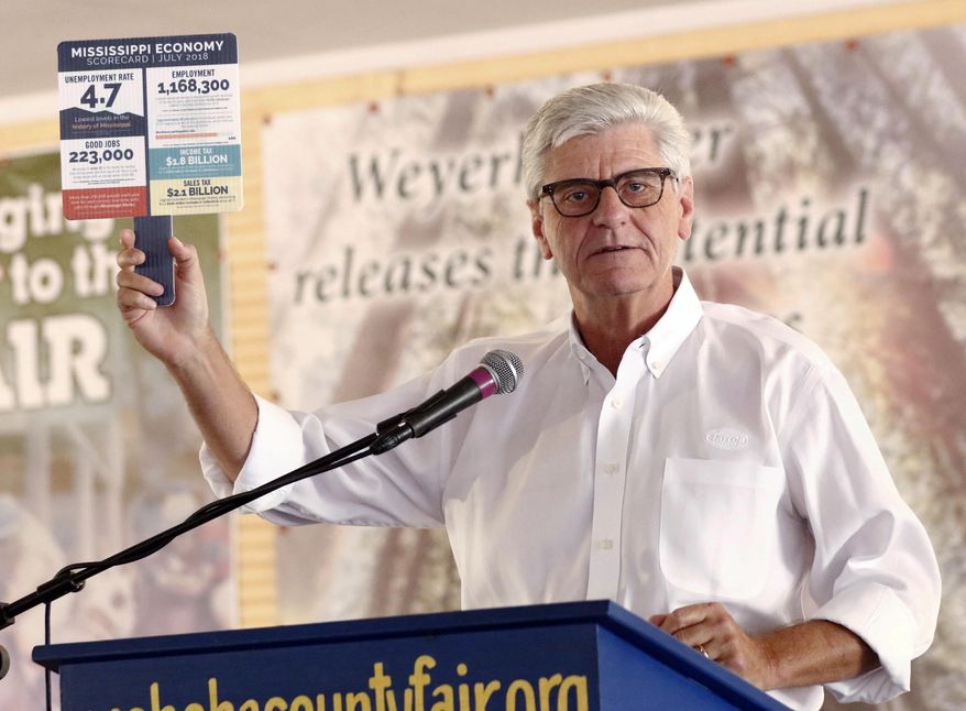 Mississippi Republican Gov. Phil Bryant holds a special hand fan with economic development facts printed on its face as he speaks Thursday , Aug. 2, 2018, at one of the biggest political events of the year in the state, the Neshoba County Fair, in Philadelphia, Miss.(AP Photo/Rogelio V. Solis)