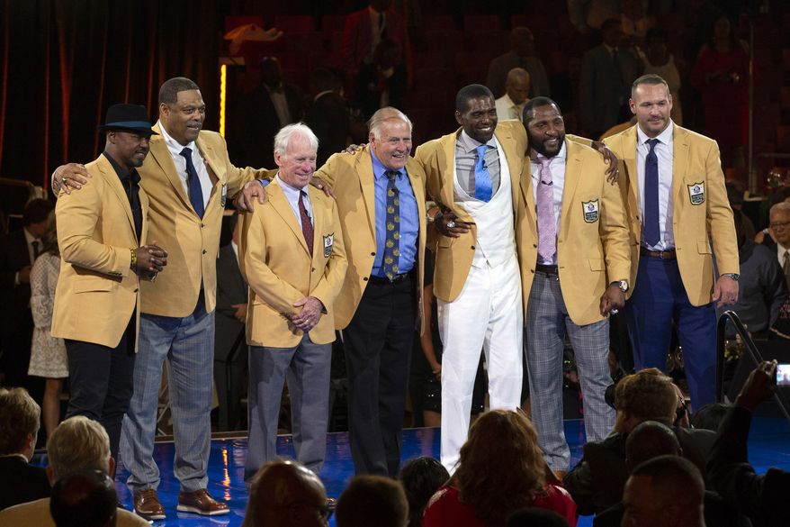 The 2018 Class of the Pro Football Hall of Fame poses during the Pro Football Hall of Fame Enshrinement Festival Enshrinee's Gold Jacket Dinner on Friday, Aug. 3, 2018, in Canton, Ohio. From left are Brian Dawkins, Robert Brazile, Bobby Beathard, Jerry Kramer, Randy Moss, Ray Lewis, and Brian Urlacher. (Bob Rossiter/The Canton Repository via AP)