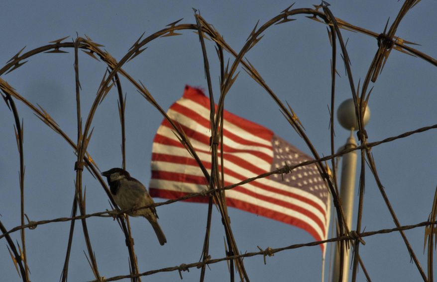 In this June 5, 2018 photo reviewed by U.S. military officials, a bird perches on barbed wire where a U.S. flag flies at the Camp VI detention facility on the Guantanamo Bay U.S. naval base in Cuba. The two Guantanamos have been a contrast since the U.S. opened the base at the southeastern tip of the island in 1903, following the Spanish-American War, and the divide has only grown under Cuba&#x27;s communist government, which refuses to cash the annual rent checks from Washington as it insists the U.S. leave. (AP Photo/Ramon Espinosa)