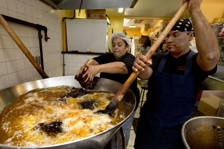 Christina Mora and Franco Hernandez start a new batch of mole at the headquarters of Mole Poblano Asuncion Corp., in the Bushwick neighborhood of Brooklyn borough of New York, Tuesday, July 31, 2018. This family-run business, that produces about 1,600 pounds of mole a day in a small Brooklyn store, has grown due to the three generations of a matriarchy that produce the dark-hued paste of ground chilies and a dozen other ingredients. (AP Photo/Richard Drew)