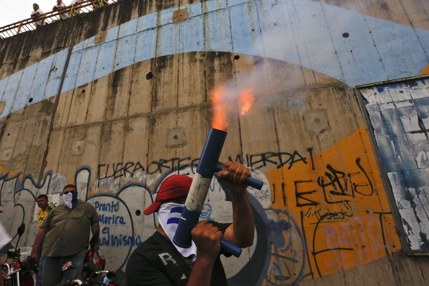 FILE - In this July 26, 2018 file photo, a demonstrator fires a home made mortar while others gather to commemorate 100 days of anti-government protests demanding the resignation of President Daniel Ortega and the release of all political prisoners, in Managua, Nicaragua. The rights group, Nicaraguan Pro-Human Rights Association, which has documented killings during months of political unrest, says it is closing its offices due to threats and harassment. (AP Photo/Alfredo Zuniga, File)
