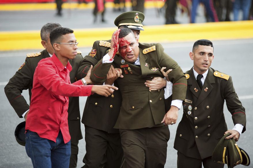 In this photo released by China&#39;s Xinhua News Agency, an uniformed official bleeds from the head following an incident during a speech by Venezuela&#39;s President Nicolas Maduro in Caracas, Venezuela, Saturday, Aug. 4, 2018. Drones armed with explosives detonated near Venezuelan President Nicolas Maduro as he gave a speech to hundreds of soldiers in Caracas on Saturday but the socialist leader was unharmed, according to the government. (Xinhua via AP)