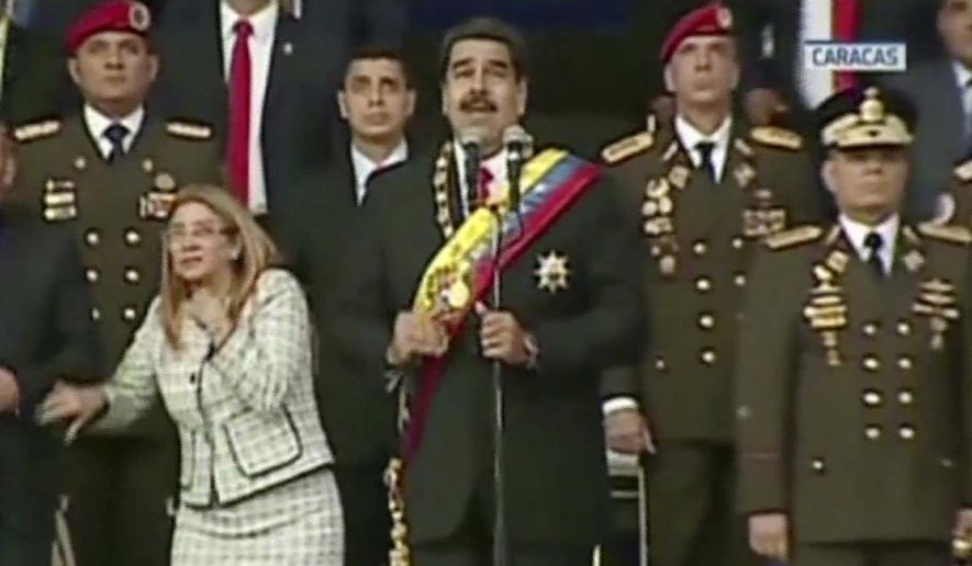 VIDEO STILL, BEST QUALITY AVAILABLE - In this still from a video provided by Venezolana de Television, Presiden Nicolas Maduro, center, delivers his speech as his wife Cilia Flores winces and looks up after being startled by and explosion, in Caracas, Venezuela, Saturday, Aug. 4, 2018. Venezuela&#39;s government says several explosions heard at a military event were an attempted attack on President Maduro. Information Minister Jorge Rodriguez said in a live broadcast that several drone-like devices with explosives detonated near the president. He said Maduro is safe and unharmed but that seven people were injured. (Venezolana de Television via AP)