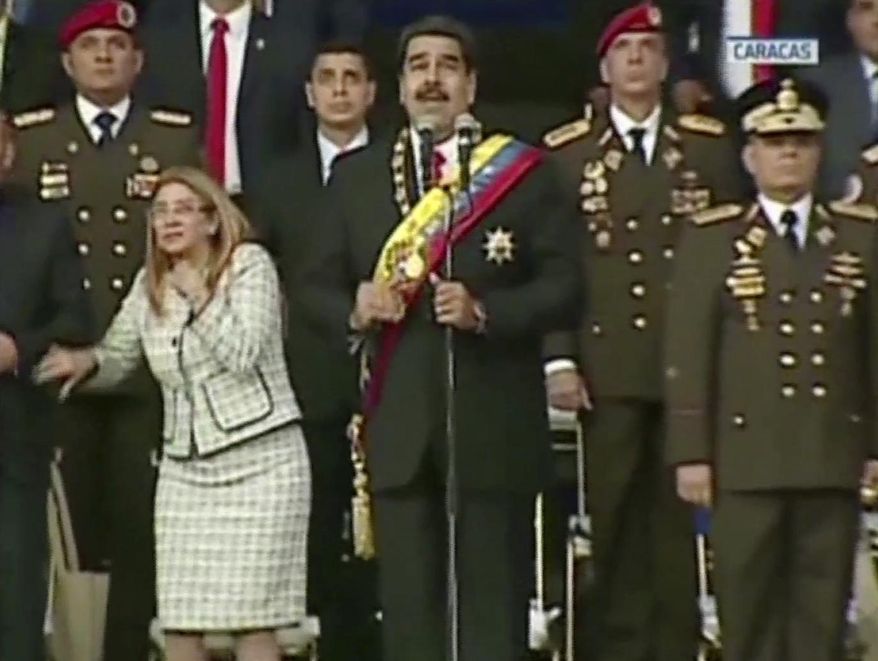 VIDEO STILL, BEST QUALITY AVAILABLE - In this still from a video provided by Venezolana de Television, Presiden Nicolas Maduro, center, delivers his speech as his wife Cilia Flores winces and looks up after being startled by and explosion, in Caracas, Venezuela, Saturday, Aug. 4, 2018. Venezuela&#39;s government says several explosions heard at a military event were an attempted attack on President Maduro. Information Minister Jorge Rodriguez said in a live broadcast that several drone-like devices with explosives detonated near the president. He said Maduro is safe and unharmed but that seven people were injured. (Venezolana de Television via AP)
