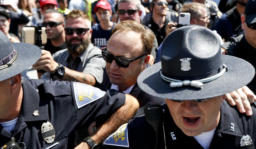 Alex Jones, center, an American conspiracy theorist and radio show host, is escorted out of a crowd of protesters after he said he was attacked in Public Square on Tuesday, July 19, 2016, in Cleveland, during the second day of the Republican convention. (AP Photo/John Minchillo)
