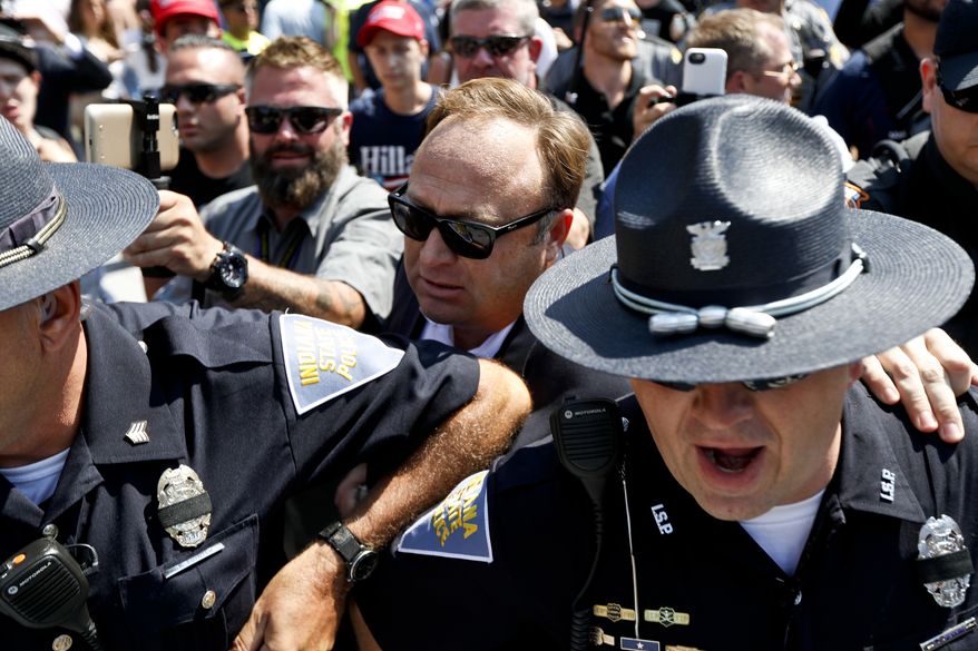 Alex Jones, center, an American conspiracy theorist and radio show host, is escorted out of a crowd of protesters after he said he was attacked in Public Square on Tuesday, July 19, 2016, in Cleveland, during the second day of the Republican convention. (AP Photo/John Minchillo)