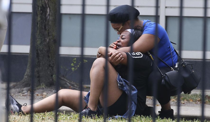 In this Sunday, Aug. 5, 2018 photo, two women cry outside the Stroger Hospital in Chicago, after they were asked to leave due to overwhelming crowds of family and friends of shooting victims. Police Superintendent Eddie Johnson plans to discuss the weekend violence during a Monday news conference. (Antonio Perez/Chicago Tribune via AP)