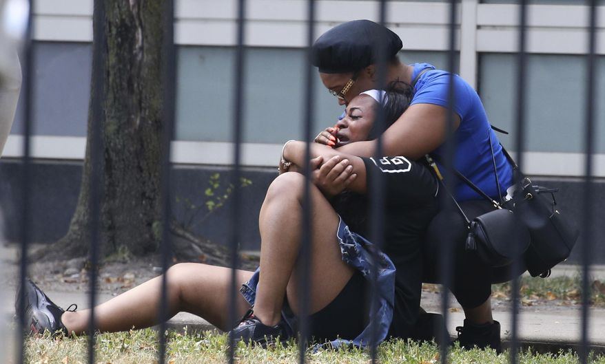 In this Sunday, Aug. 5, 2018 photo, two women cry outside the Stroger Hospital in Chicago, after they were asked to leave due to overwhelming crowds of family and friends of shooting victims. Police Superintendent Eddie Johnson plans to discuss the weekend violence during a Monday news conference. (Antonio Perez/Chicago Tribune via AP)