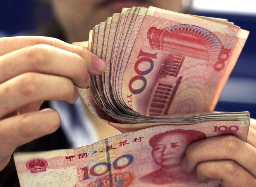 FILE - In this photo taken on Aug. 25, 2010, a bank clerk counts Chinese 100 Yuan notes in Shanghai. China has tightened controls on trading in its yuan following a decline against the dollar that raised the risk of a damaging outflow of capital from the world’s second-largest economy. (AP Photo/Eugene Hoshiko, File)