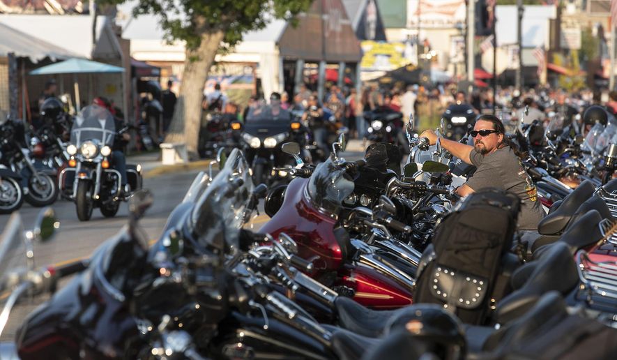 In this Saturday, Aug. 4, 2018, photo, Rob Gregory, of Knoxville, Tenn., sits on his motorcycle parked along Main Street in Sturgis, S.D., during the 78th annual Sturgis Motorcycle Rally. (Ryan Hermens/Rapid City Journal via AP)