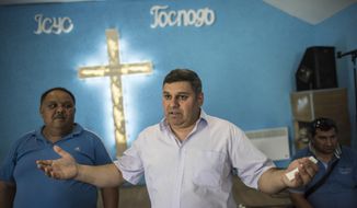 In this photo taken on Monday, June 4, 2018 and provided by OSCE Project Co-ordinator in Ukraine Press Service, Roma activist Myroslav Horvat of the World Roma Organization, center, gestures while speaking to journalists in a church inside a Roma encampment on the outskirts of Uzhhorod, western Ukraine. After attackers charged into a Roma encampment on the outskirts of Kiev, a leader of an ultranationalist group posted photos of his colleagues clearing the site and burning tents left behind. The April attack was the first of 11 forced removals that civilians in Ukraine carried out at Roma settlements an ethnic group, also known as Gypsies, that faces discrimination and disdain in much of Europe. (Evgeniy Malolletka,OSCE Project Co-ordinator Press Service via AP)