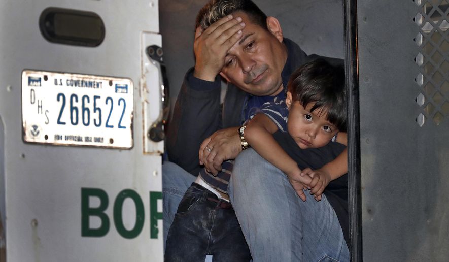 A father and his 3-year-old son are detained in the back of a U.S. Customs and Border Patrol vehicle Wednesday, July 18, 2018 in San Luis, Ariz. The boy, his father and two siblings were arrested by a U.S. Border Patrol agent who spotted them crossing a canal along the the international border. (AP Photo/Matt York)