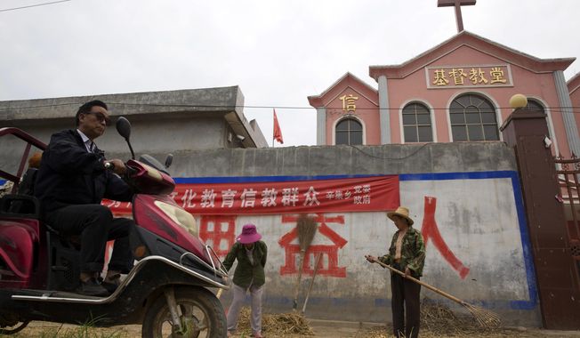 FILE - In this photo taken Saturday, June 2, 2018, a man rides past workers tossing hay outside a church with part of a slogan that reads &amp;quot;Educate the believers with excellent Chinese traditional culture&amp;quot; near the city of Pingdingshan in central China&#x27;s Henan province. Under President Xi Jinping, China&#x27;s most powerful leader since Mao Zedong, believers are seeing their freedoms shrink dramatically even as the country undergoes a religious revival. Experts and activists say that as he consolidates his power, Xi is waging the most severe systematic suppression of Christianity in the country since religious freedom was written into the Chinese constitution in 1982. (AP Photo/Ng Han Guan)