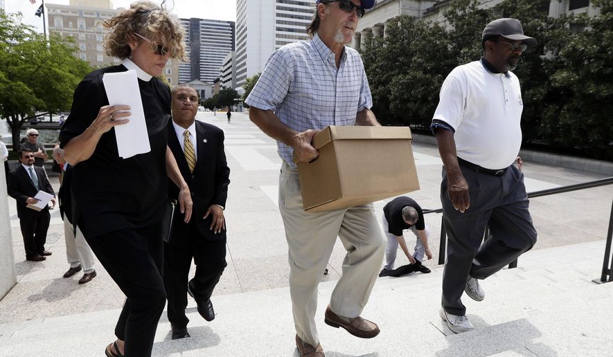 Ray Krone, center, who was the 100th inmate exonerated from death row since the death penalty was reinstated, carries a box of petition signatures to be delivered to Gov. Bill Haslam after a protest against the death penalty Tuesday, Aug. 7, 2018, in Nashville, Tenn. At left is Rev. Stacy Rector. Attorneys are asking the U.S. Supreme Court for a stay of execution for convicted child killer Billy Ray Irick after the Tennessee Supreme Court and governor decided against a delay. (AP Photo/Mark Humphrey)