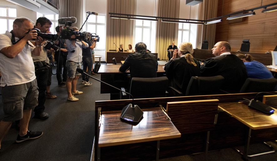 Photographers take pictures of the a man and a woman in the court in Freiburg, southern Germany, Tuesday, Aug. 7, 2018 before they were sentenced to long-term prison sentence for for offering the 9-year-old son of the woman for raping by pedophiles. (Patrick Seeger/dpa via AP)