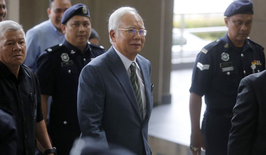 Former Malaysian Prime Minister Najib Razak, center, arrives at High Court of Malaya in Kuala Lumpur, Malaysia, Wednesday, Aug. 8, 2018. Najib will face a new charge of money laundering over a multibillion-dollar graft scandal at a state investment fund, the anti-corruption agency said. Najib in July pleaded not guilty to abuse of power and three counts of criminal breach of trust, just two months after the scandal led to his stunning election defeat. (AP Photo/Yam G-Jun)