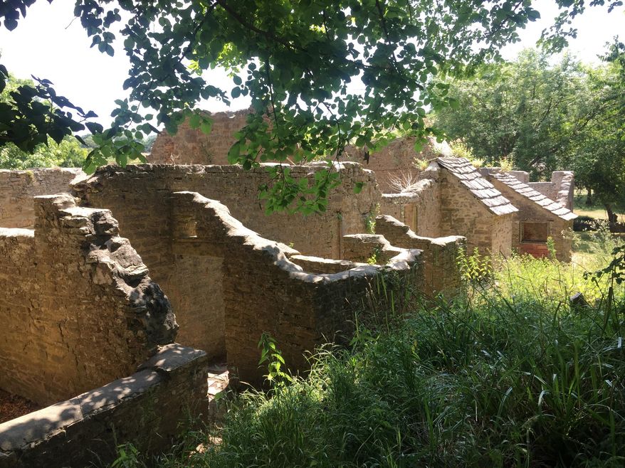 In this July 8, 2018 photo, grass and nettles grow up around a row of abandoned, dilapidated cottages in the "ghost village" of Tyneham, in Dorset, England. The tiny settlement was evacuated on War Department orders in 1943, to provide more land for training ahead of D-Day in World War II. The people were never allowed to return, and it remains in military hands. Visitors are allowed in most weekends to see what is a poignant reminder of the days of WWII. (AP Photo/Jerry Harmer)