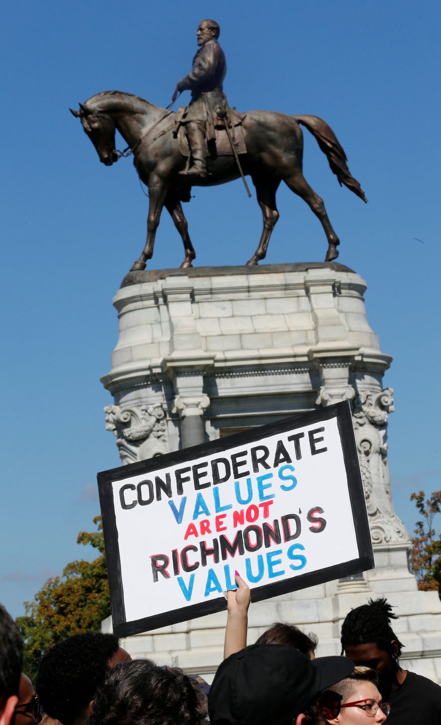 Counter protesters hold signs in front of the statue of Confederate General Robert E. Lee on Monument Avenue in Richmond, Va., Saturday, Sept. 16, 2017. The group of Confederate demonstrators were escorted out by police after a 50 minute protest. (AP Photo/Steve Helber)