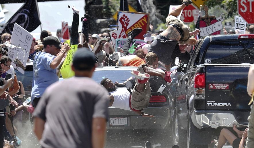 In this Aug. 12, 2017, file photo, people fly into the air as a vehicle drives into a group of protesters demonstrating against a white nationalist rally in Charlottesville, Va. Efforts to take down Americas monuments honoring slain Confederate soldiers and the generals who led them gained explosive momentum following the deadly violence a year ago in Charlottesville. The vehicle plowed into a crowd protesting a gathering of white supremacists whose stated goal was to protect a statue of Gen. Robert E. Lee. (Ryan M. Kelly/The Daily Progress via AP, File)
