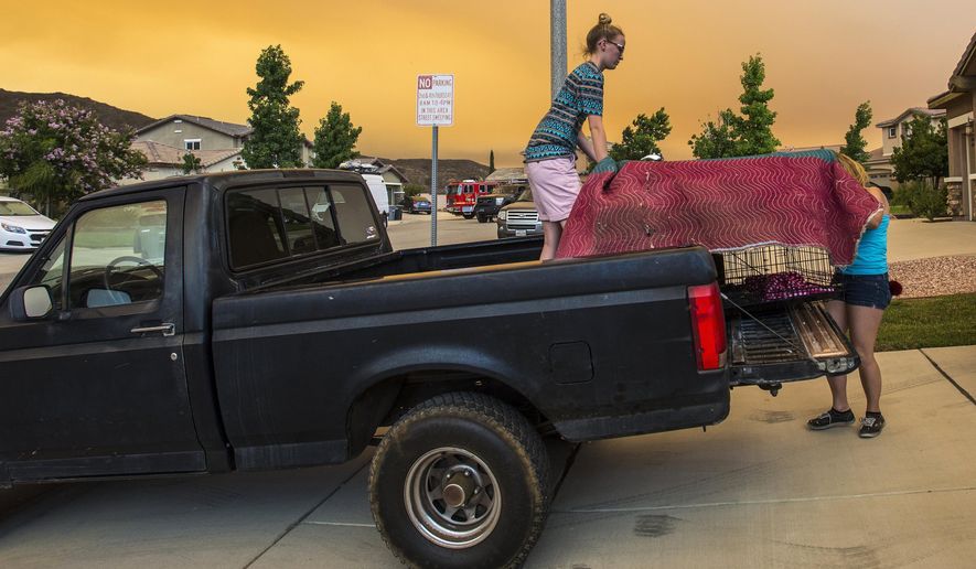 Residents along Crystal Ridge Court in Lake Elsinore, Calif., load a truck as they evacuate as the Holy Fire burns near their home on Wednesday, Aug. 8, 2018. (Mark Rightmire/The Orange County Register via AP)