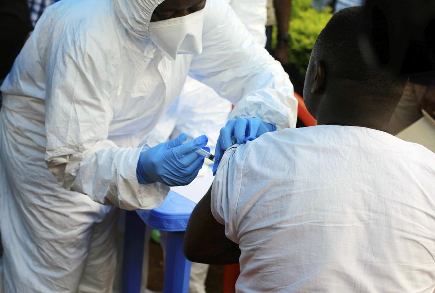 A healthcare worker from the World Health Organization gives an Ebola vaccination to a front line aid worker in Mangina, Democratic Republic of Congo, Wednesday, Aug 8, 2018. Health experts began Ebola vaccinations in Congo's northeast village of Mangina for the latest deadly outbreak that has already claimed at least nine lives. (AP Photo/Al-hadji Kudra Maliro)