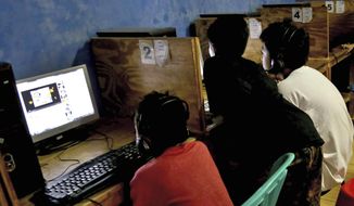 In this Monday, Dec. 23, 2013, file photo, youths look at computer screens at an internet cafe in Jakarta, Indonesia. (AP Photo/Tatan Syuflana) ** FILE **