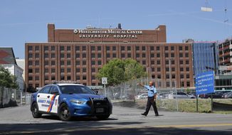 A Westchester Medical Center security guard directs traffic as a Westchester County police car pulls out of the drive to the main entrance of the hospital, Wednesday, Aug. 8, 2018, in Valhalla, N.Y. A man shot a female patient and then killed himself at the suburban New York hospital Wednesday, police said.(AP Photo/Julie Jacobson)