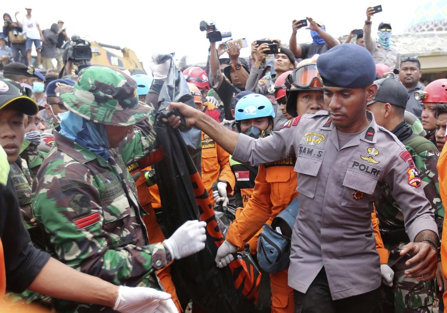 Emergency workers recover a body from the Jamiul Jamaah Mosque after it collapsed during an earthquake in Bangsal, North Lombok, Indonesia, Wednesday, Aug. 8, 2018. The north of Lombok was devastated by the powerful quake that struck Sunday night, damaging thousands of buildings and killing a large number of people. Rescuers were still struggling to reach all of the affected areas and authorities expect the death toll to rise. (AP Photo/Tatan Syuflana)