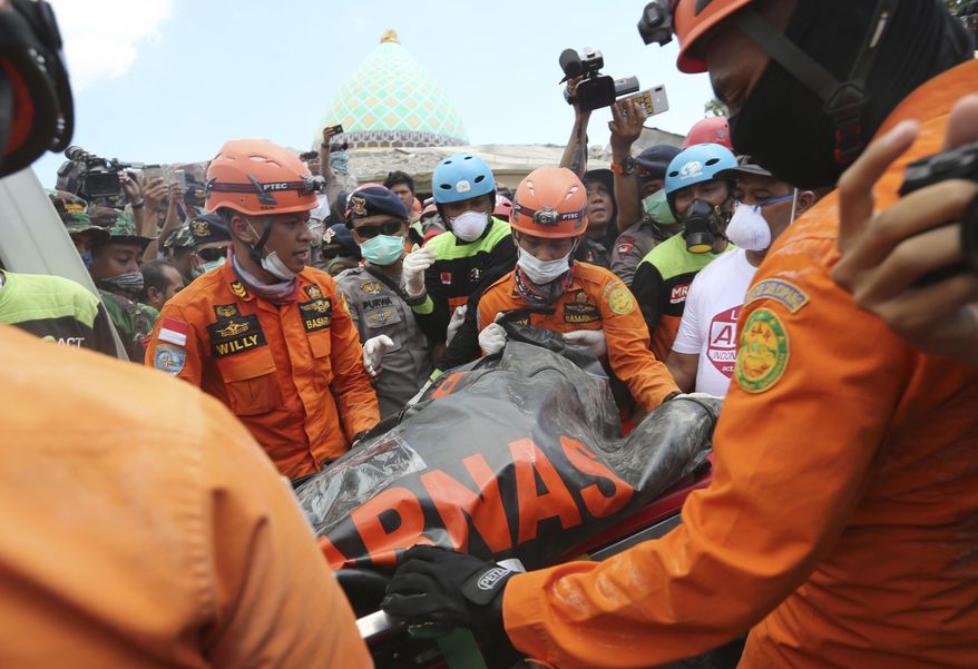 Emergency workers recover a body from the Jamiul Jamaah Mosque after it collapsed during an earthquake in Bangsal, North Lombok, Indonesia, Wednesday, Aug. 8, 2018. The north of Lombok was devastated by the powerful quake that struck Sunday night, damaging thousands of buildings and killing a large number of people. Rescuers were still struggling to reach all of the affected areas and authorities expect the death toll to rise. (AP Photo/Tatan Syuflana)