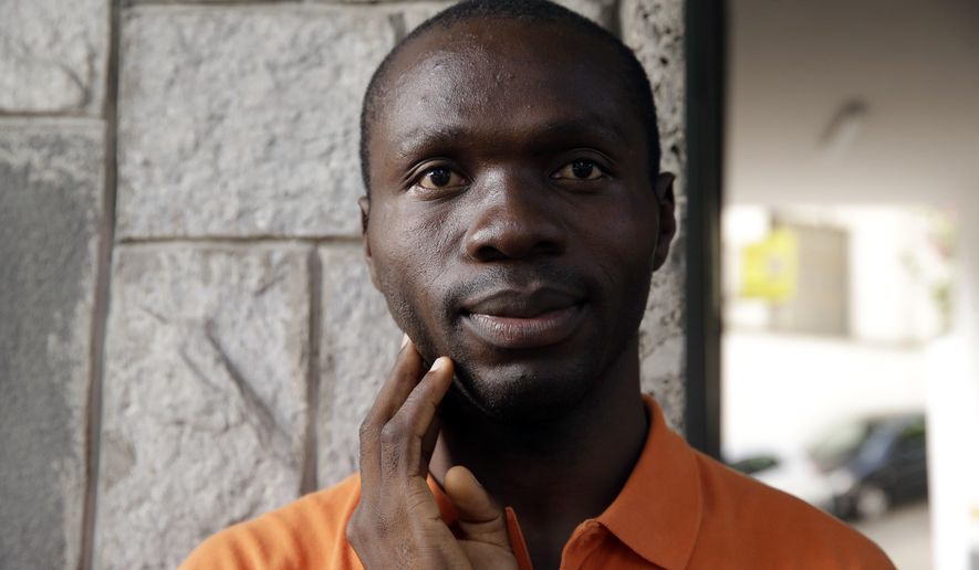 In this photo taken on Wednesday, Aug. 1, 2018, asylum seeker Ogochukwu Efeizomor, from Nigeria, 30, poses for a photograph as he begs in Milan, Italy. A Nigerian asylum-seeker in Italy spends his time begging or learning Italian as he waits for a decision on his application, while anti-migrant tensions rise under Italy’s new populist government. (AP Photo/Luca Bruno)